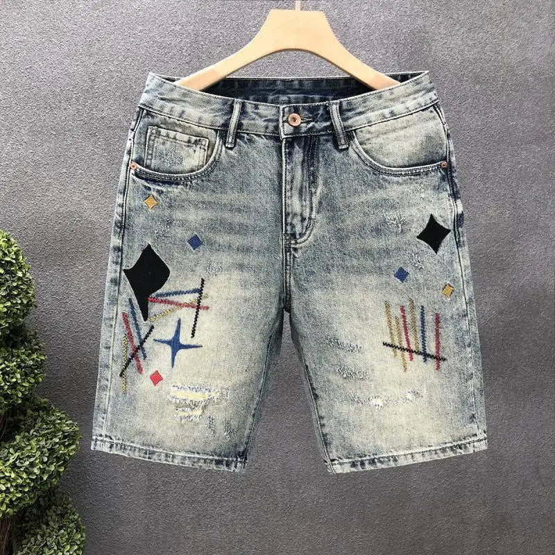 Denim shorts with geometric patterns on a hanger against a gray background