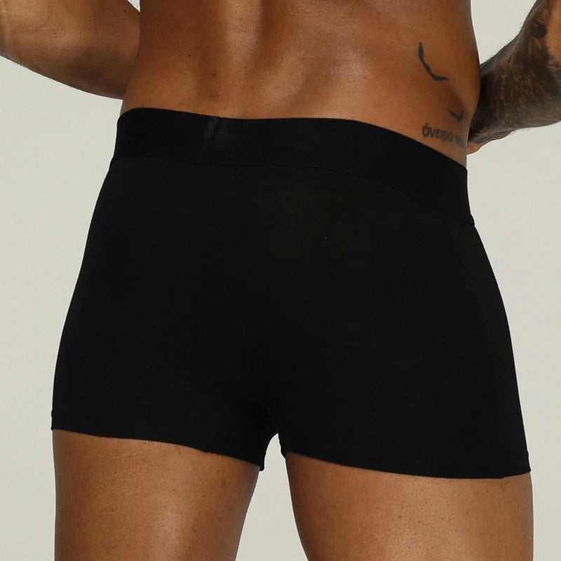 Person wearing black underwear on a neutral background