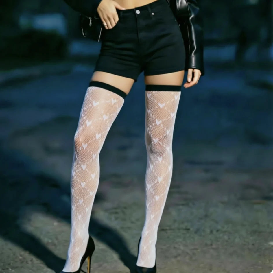Person wearing sheer white stockings with heart patterns and black high-waisted shorts.