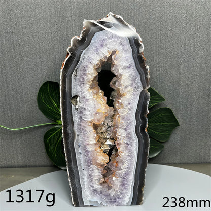 Geode crystal on a gray background with green leaves