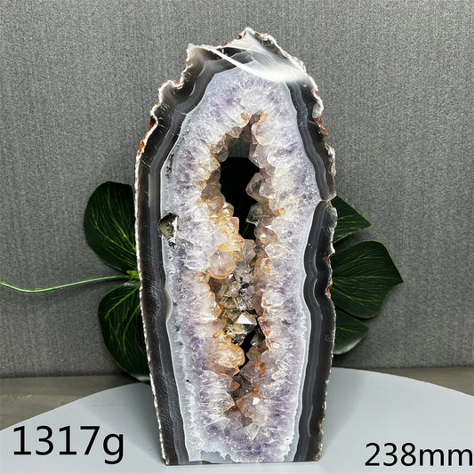 Geode crystal on a gray background with green leaves
