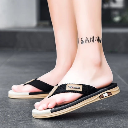 Black and beige sandals worn by a person on a gray floor.