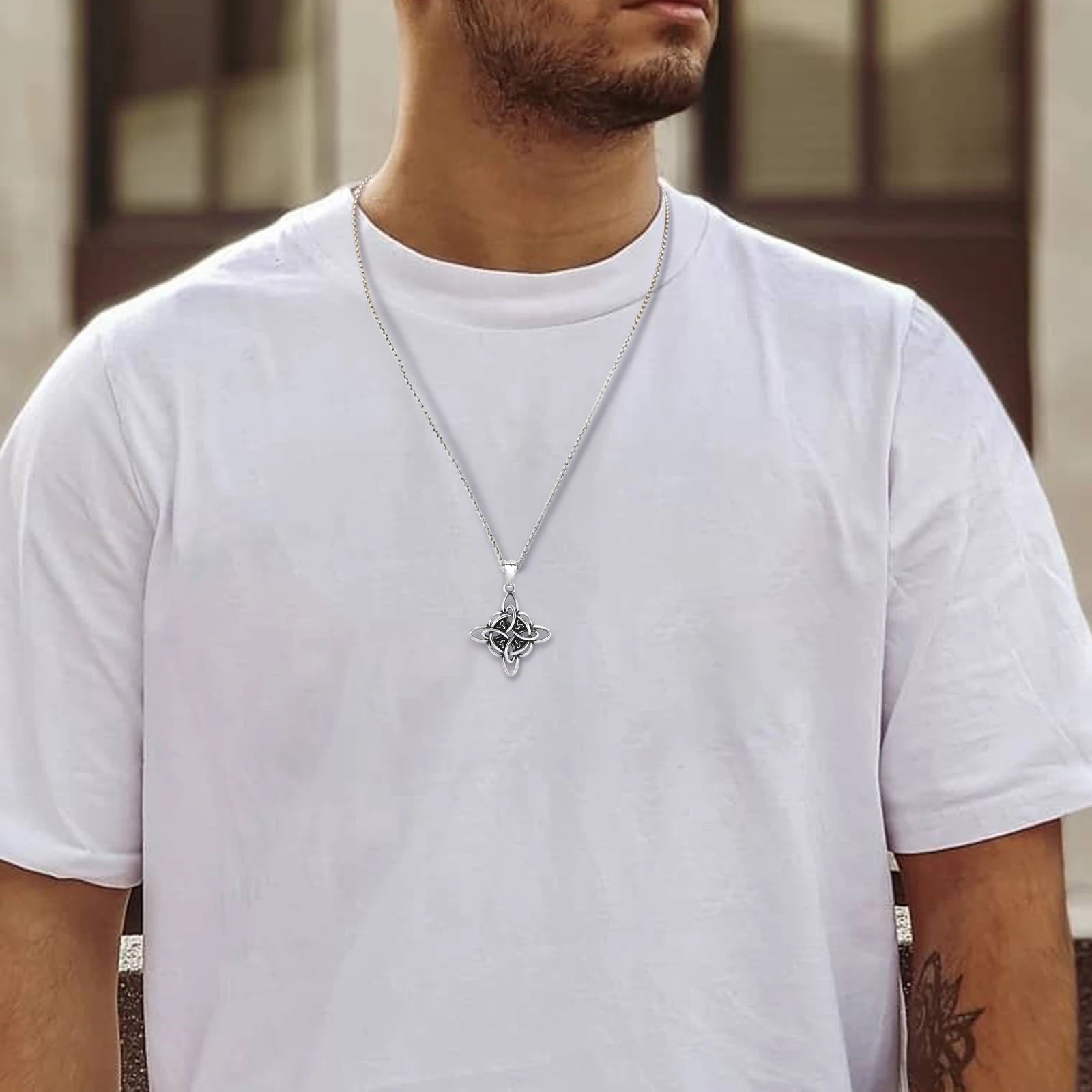 Man wearing a Vnox stainless steel Celtic Knot amulet necklace with a silver Triquetra pendant on a white t-shirt.