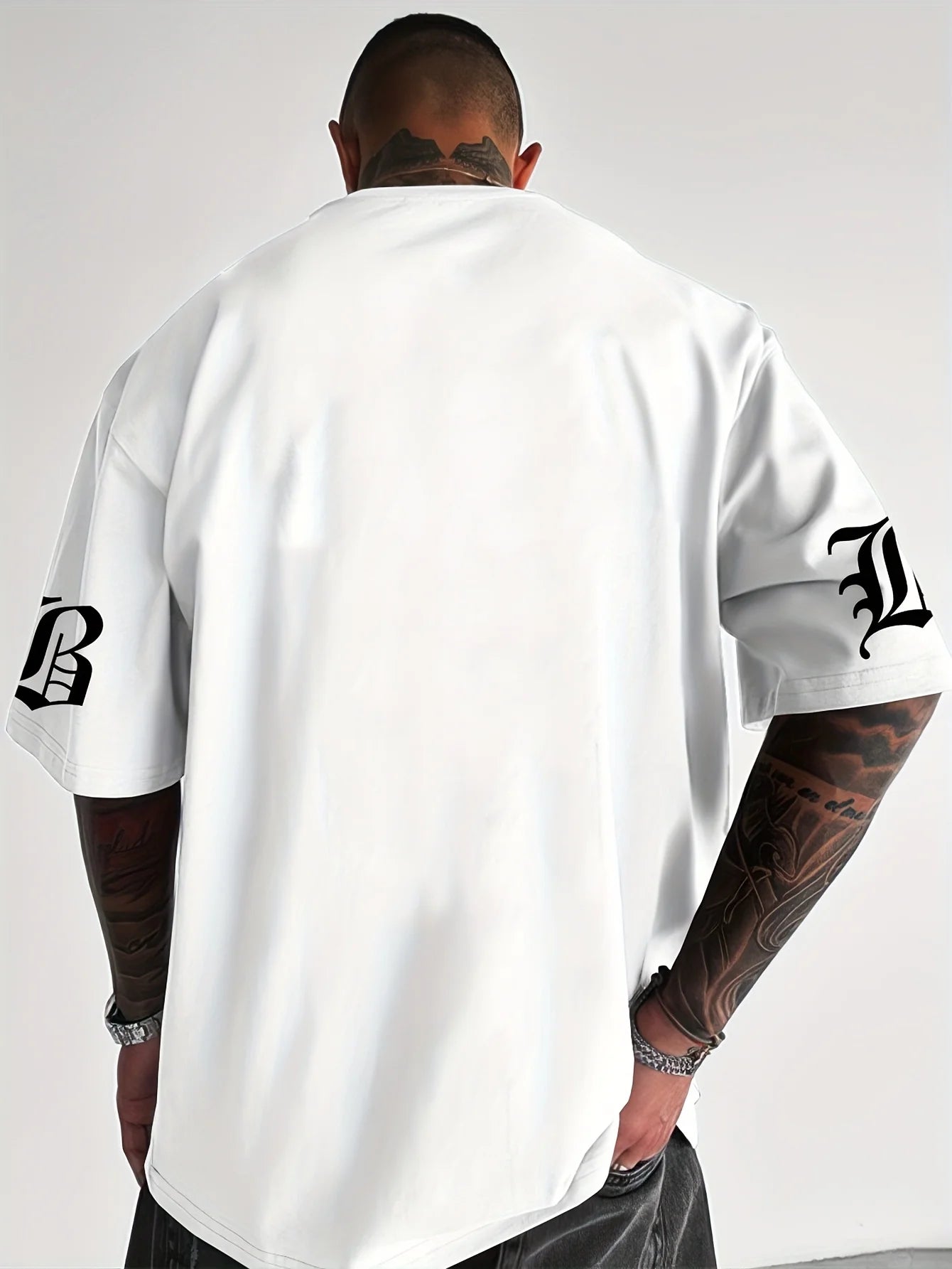 Person wearing a white t-shirt with black logos on a plain background