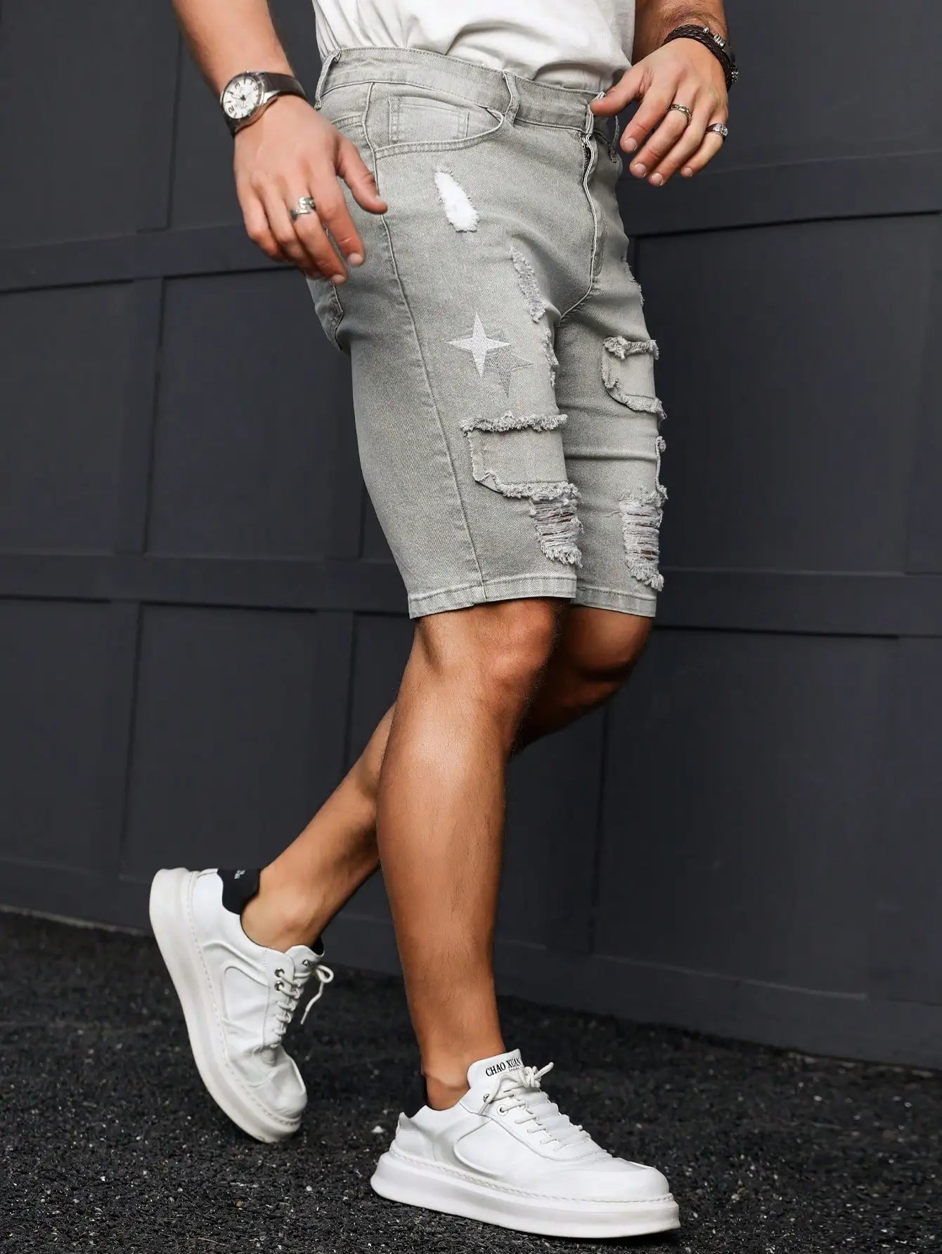 Person wearing gray shorts and white sneakers against a dark background