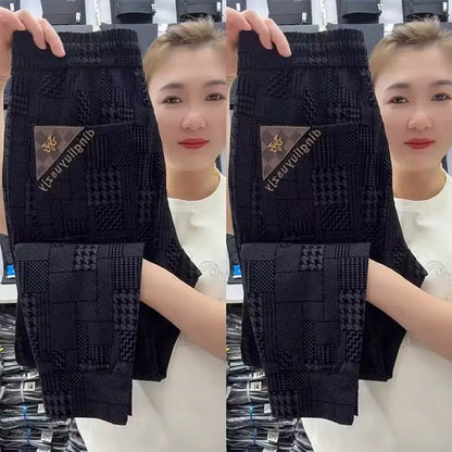 Person holding black patterned socks with a brand logo, wearing a white shirt.