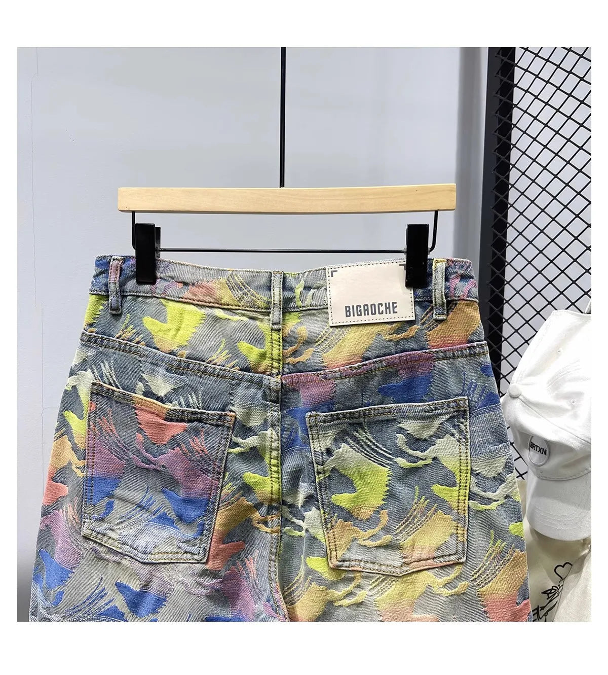 Colorful patterned denim shorts on a hanger with a visible brand label.