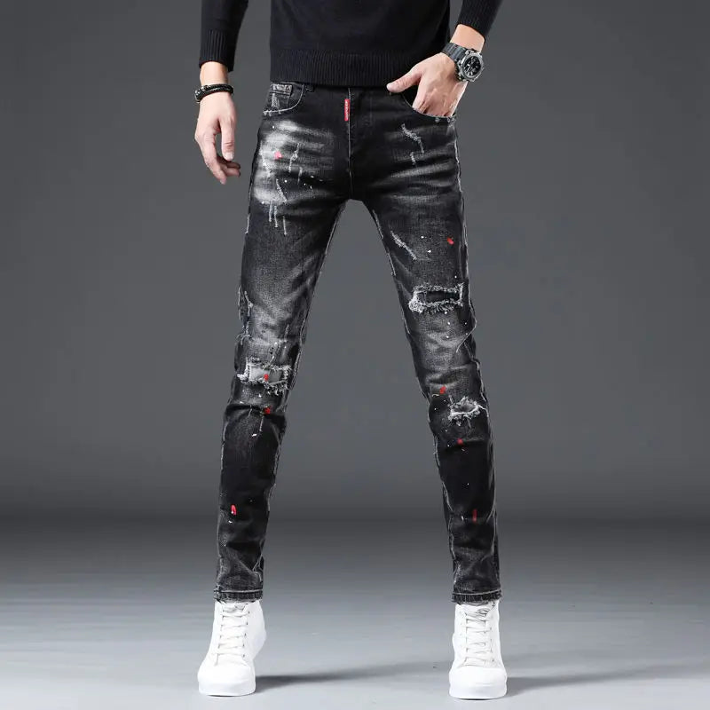 Person wearing black distressed jeans on a gray background