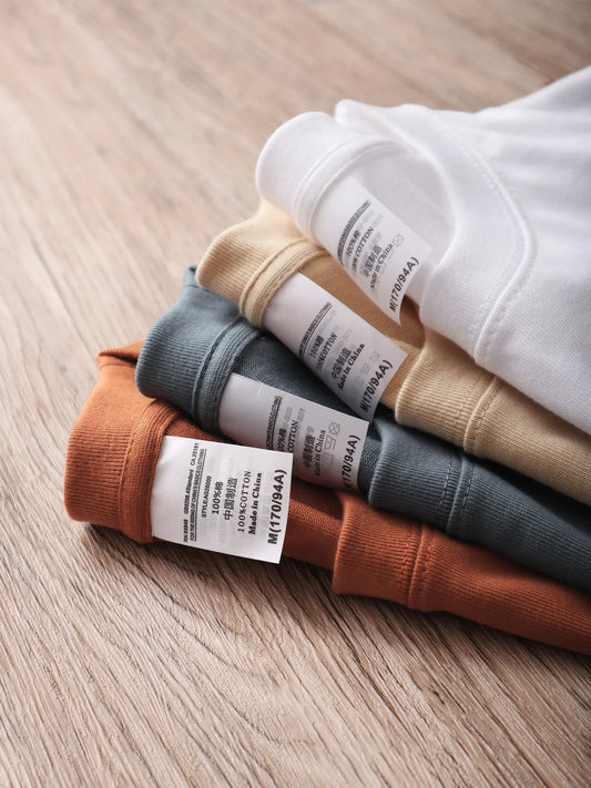 Stack of folded shirts with labels on a wooden surface