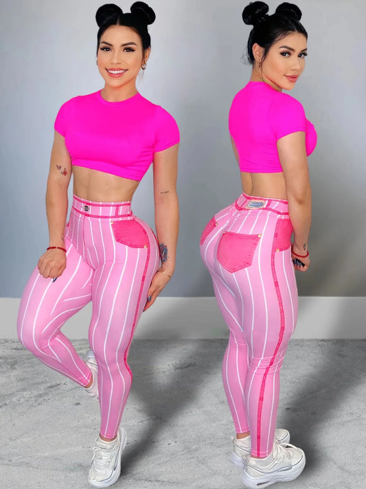 Woman wearing a pink crop top and striped leggings posing against a gray background