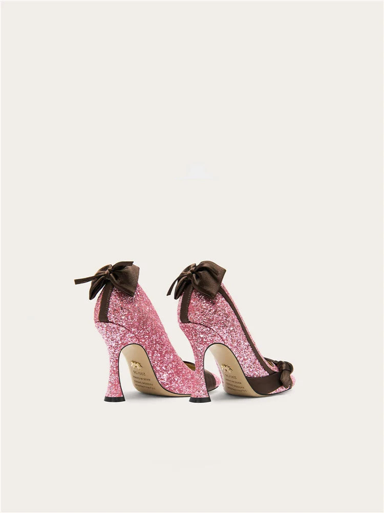 Pink glitter high heels with brown bows on a light gray background