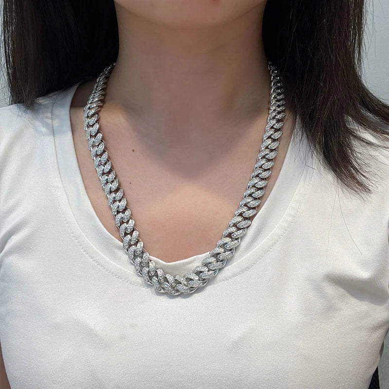 Person wearing a silver chain necklace on a plain background