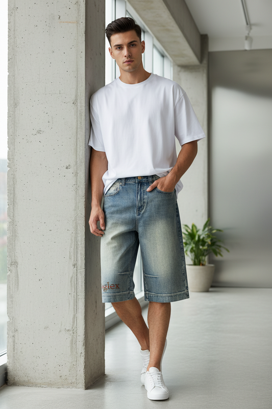 Man wearing a white t-shirt and denim shorts standing in a modern indoor setting.