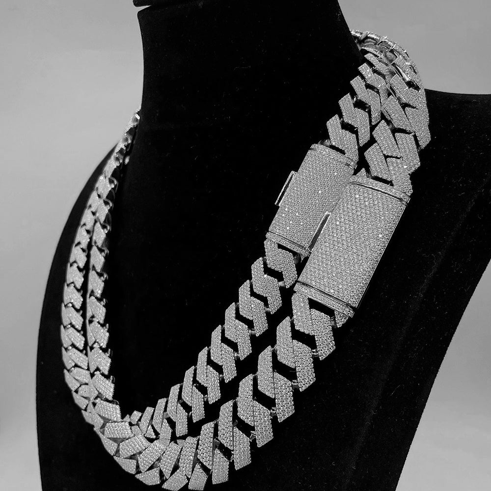 Silver chain necklace on a black stand against a gray background